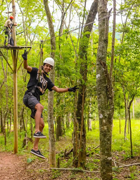 Participante deslizando entre as copas das árvores no Canopy